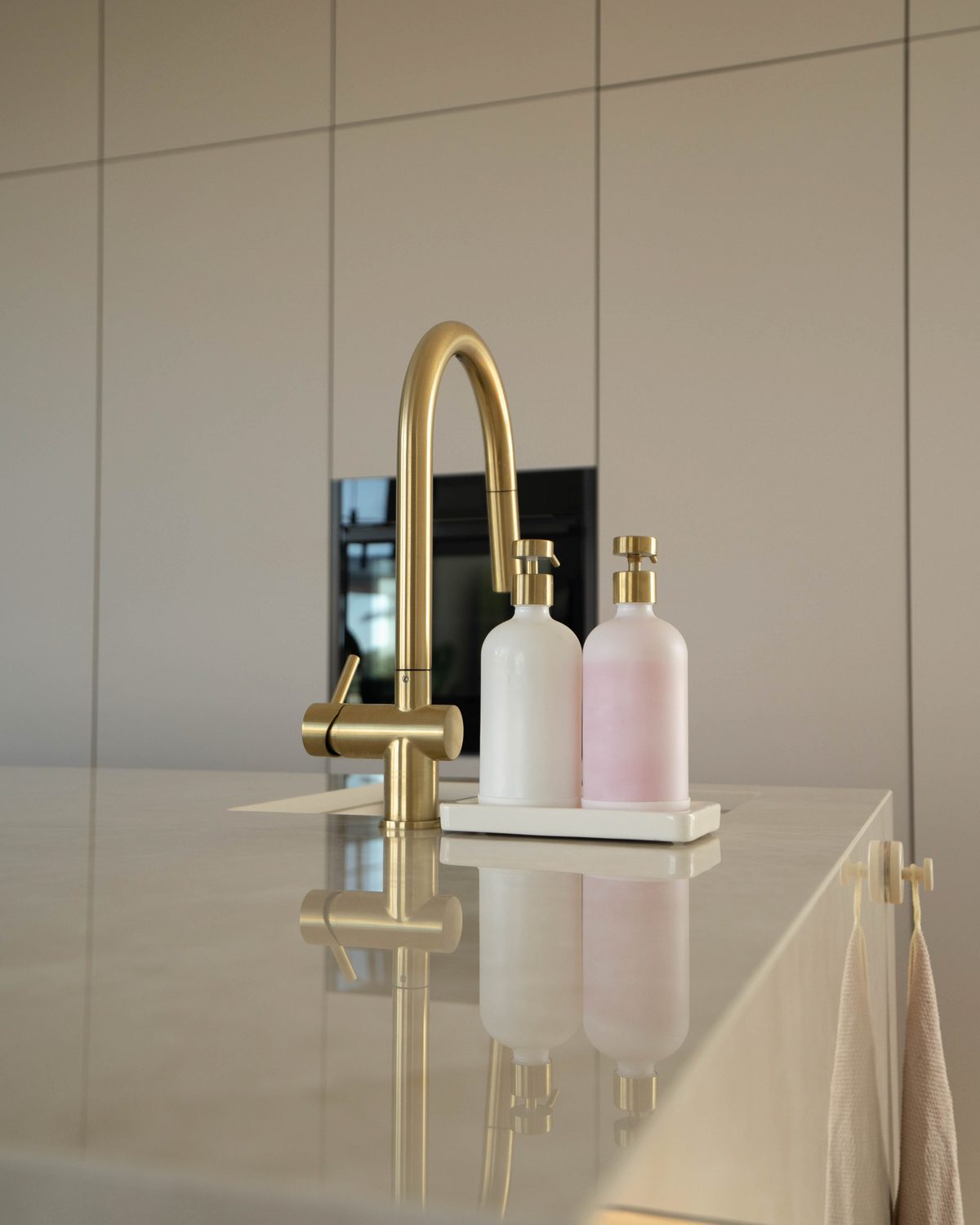 Detailaufnahme: goldene Armatur auf heller Keramik-Arbeitsplatte
